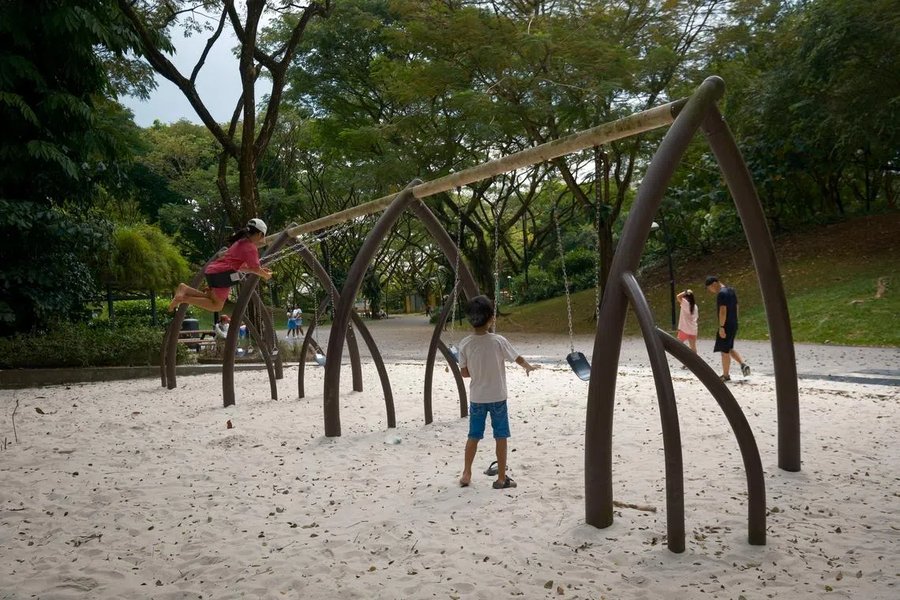 Children playing on a sand playground with a row of swings