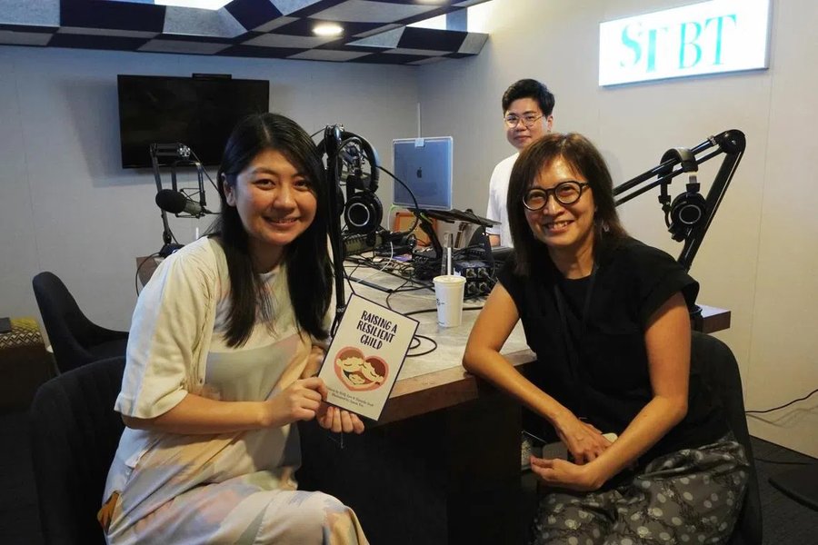 Danielle Seah recording The Straits Times' Health Check Podcast, holding a copy of Raising A Resilient Child