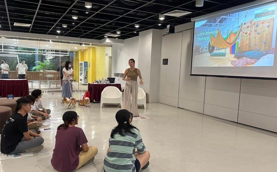 A Little Marvels therapist presenting to Ngee Ann Polytechnic students with two therapy dogs